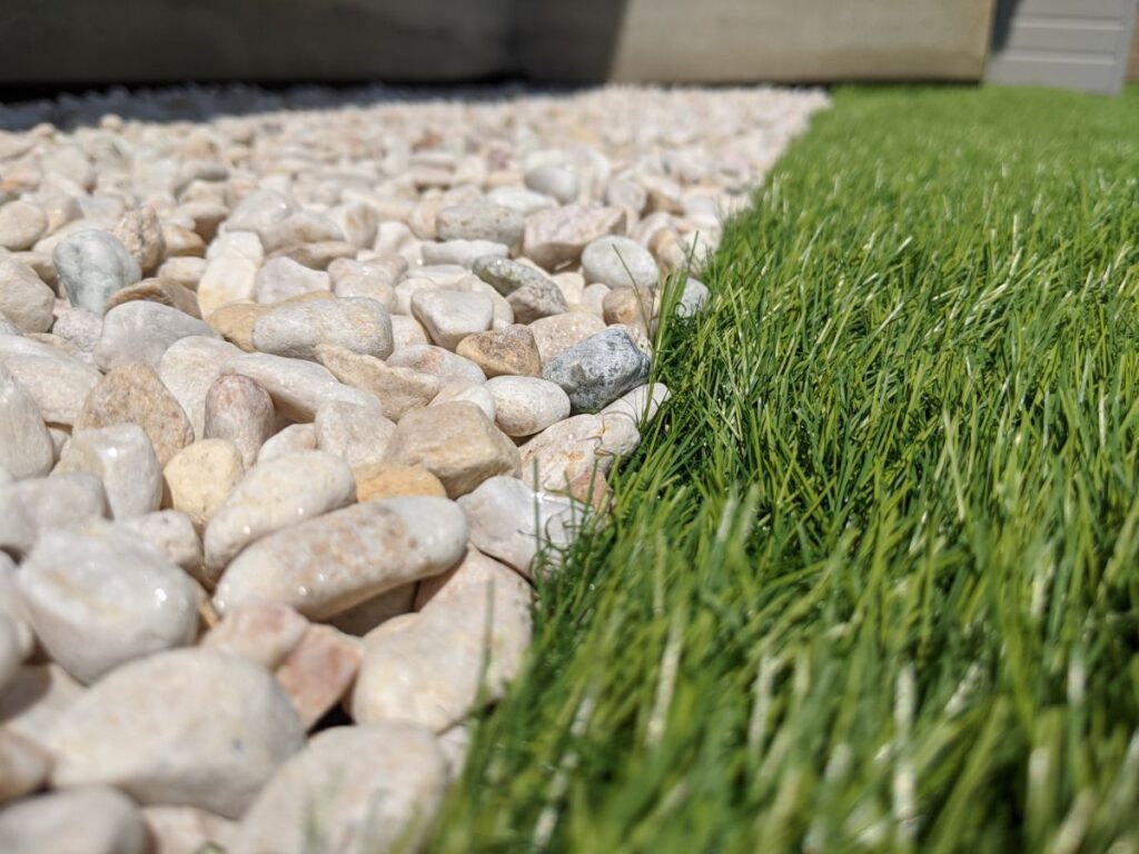 白い砂利と緑の人工芝が並んで配置された庭の一部。素材の質感と色のコントラストが分かる。