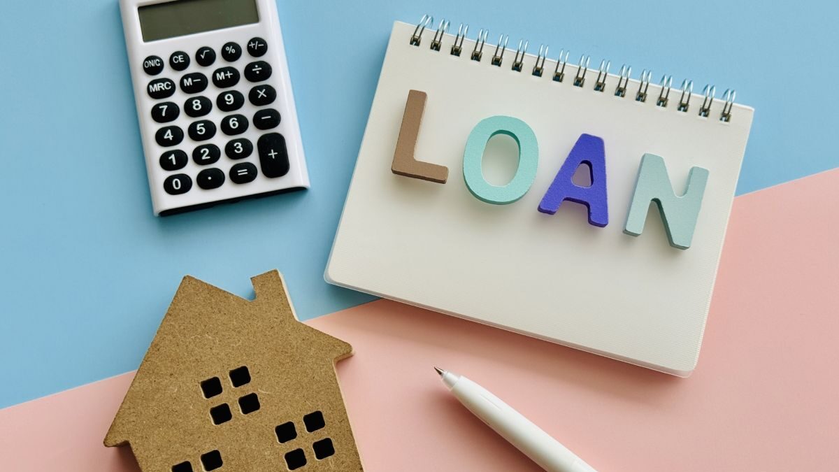 A photo of a house-shaped model, calculator, notebook, and pen, representing the concept of a home loan.