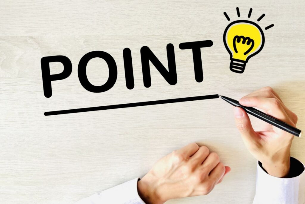 木目のテーブルの上に「POINT」と書かれた文字と電球のイラスト。メンズVIO脱毛の重要なポイントや注意点を解説する場面に最適なイメージ。
