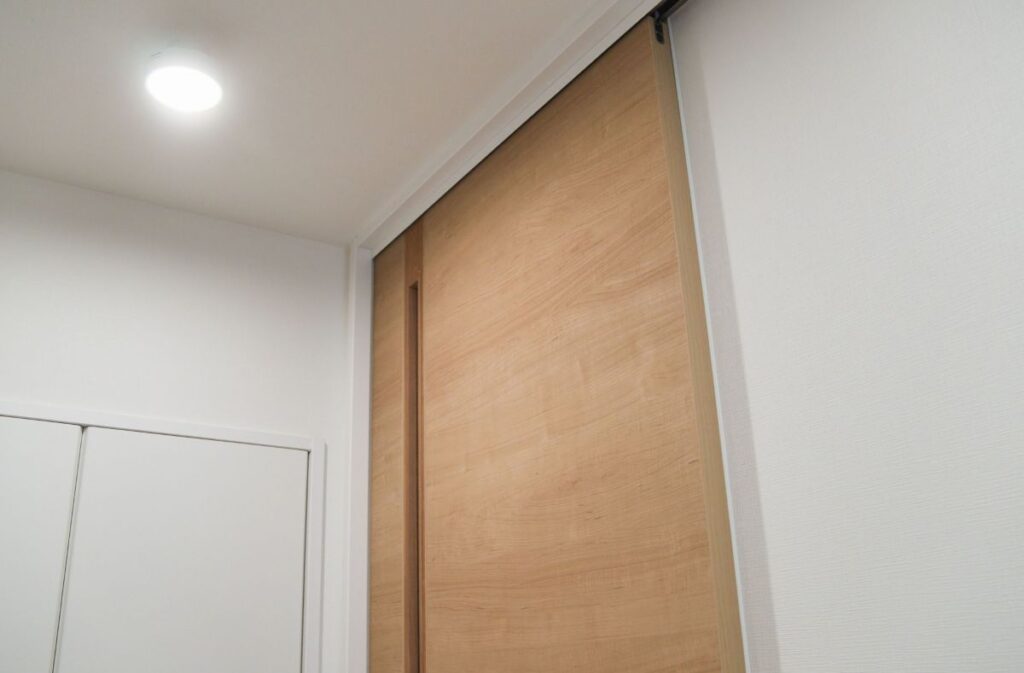 木製の片引き戸を近くから捉えた写真。シンプルな木目と取手のないミニマルデザインが特徴。