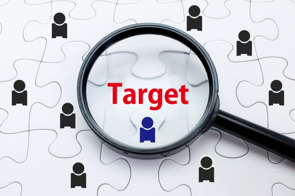 パズル背景に人物アイコンが散らばり、中央を虫眼鏡で拡大したターゲット選定のイメージ写真。