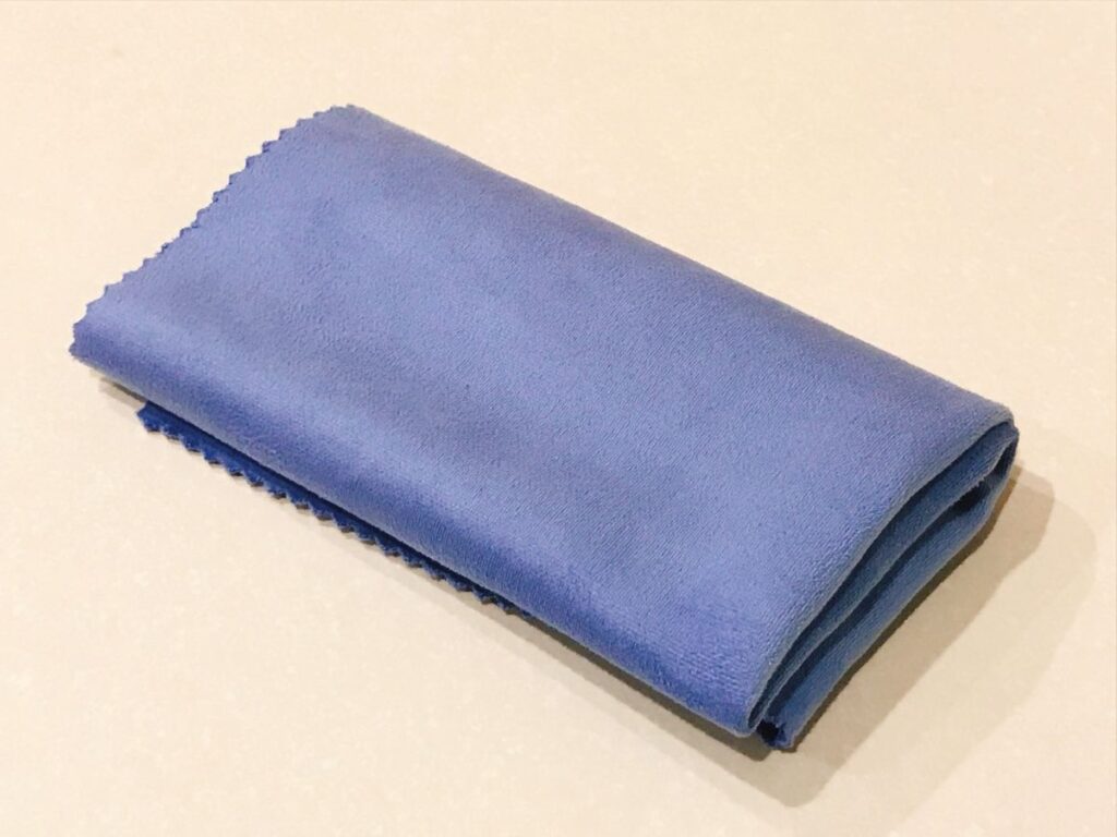 折りたたまれた青色のお手入れクロスがテーブルに置かれている様子。
