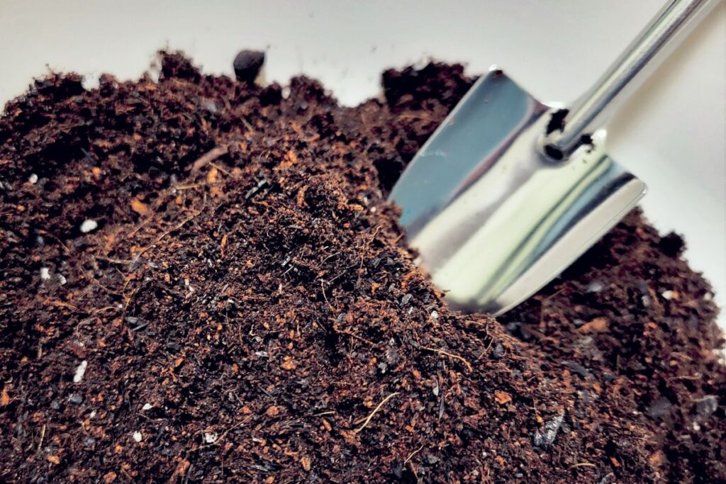 土とスコップが写され、ペットの土葬や埋葬作業を連想させるクローズアップ画像。