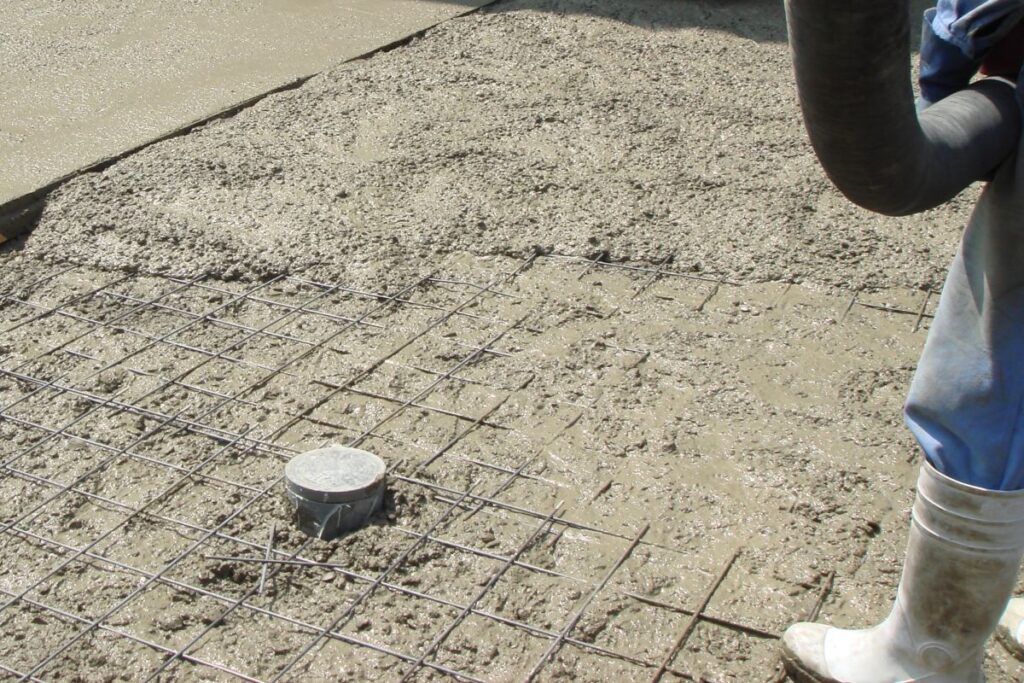 ワイヤーメッシュの上にコンクリートを流し込み、施工を進めている最中のコンクリート打設作業を捉えた画像。