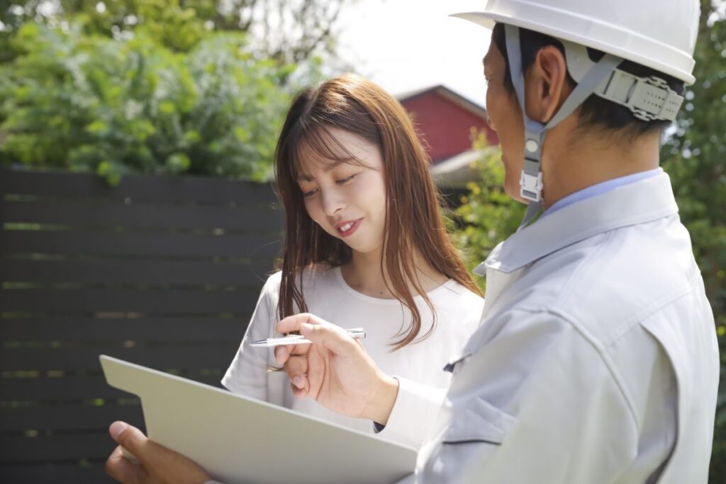 外構工事の担当者が資料を示しながら、依頼者の女性と打ち合わせを行っている様子を写した画像。