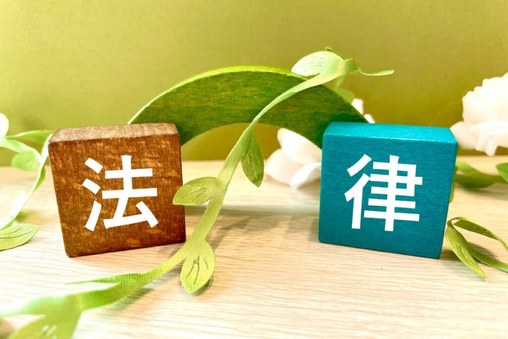 「法律」と書かれた木製ブロックが並び、ペット埋葬に関する法規をイメージさせる画像。