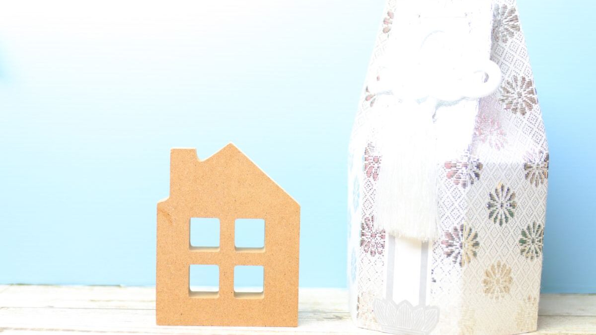 An urn placed beside a small house ornament to symbolize a home-based pet memorial.