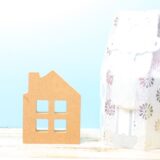 An urn placed beside a small house ornament to symbolize a home-based pet memorial.