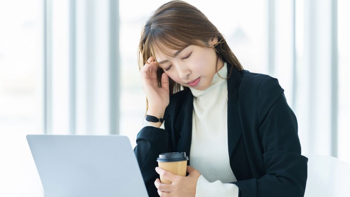 Image showing a woman holding her head at work due to ringing in the ears and dizziness.