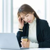 Image showing a woman holding her head at work due to ringing in the ears and dizziness.