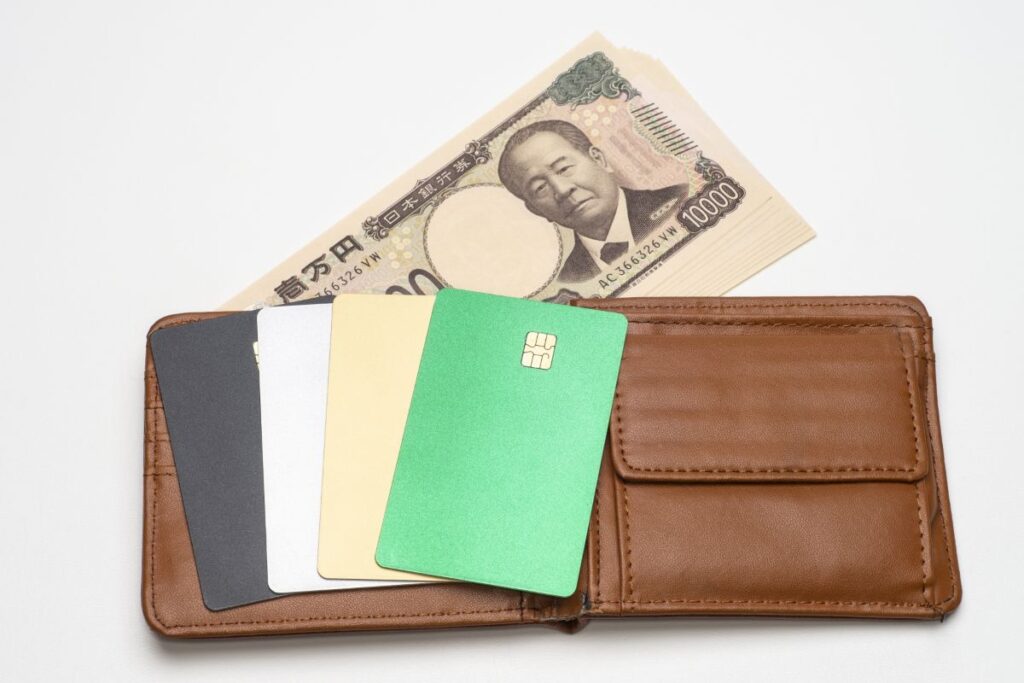 財布に現金や複数のカードが入っている。普段財布に入れる物のイメージ。