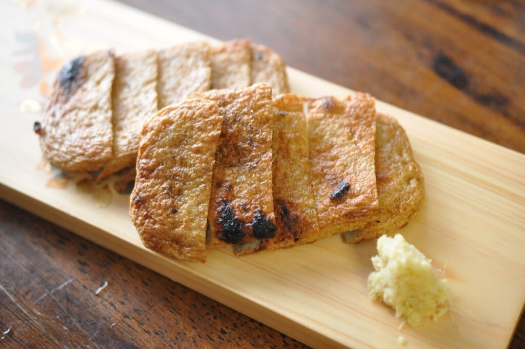 木製プレートの上に盛り付けられた、焼き色のついた宇和島特産じゃこ天と添えられたおろし生姜