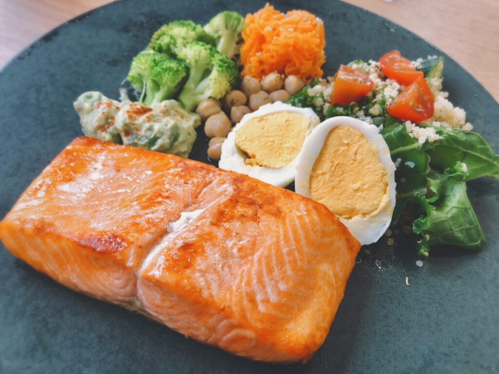 髪の健康に良いタンパク質を豊富に含む、焼き鮭とゆで卵、ブロッコリーのヘルシーなプレート料理