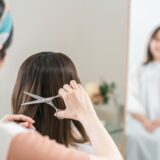 A woman looking in the salon mirror to check her beautiful, improved hair after a professional cut and treatment.