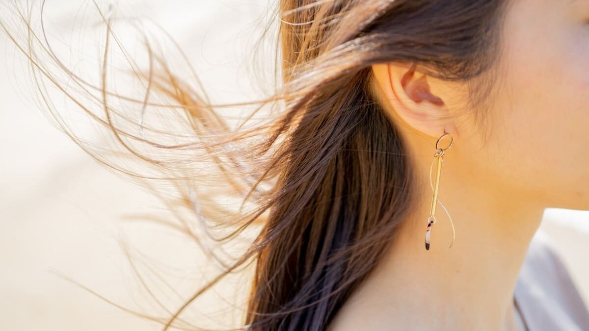Close-up profile shot of a woman with healthy, shiny hair fluttering in the wind under natural sunlight.