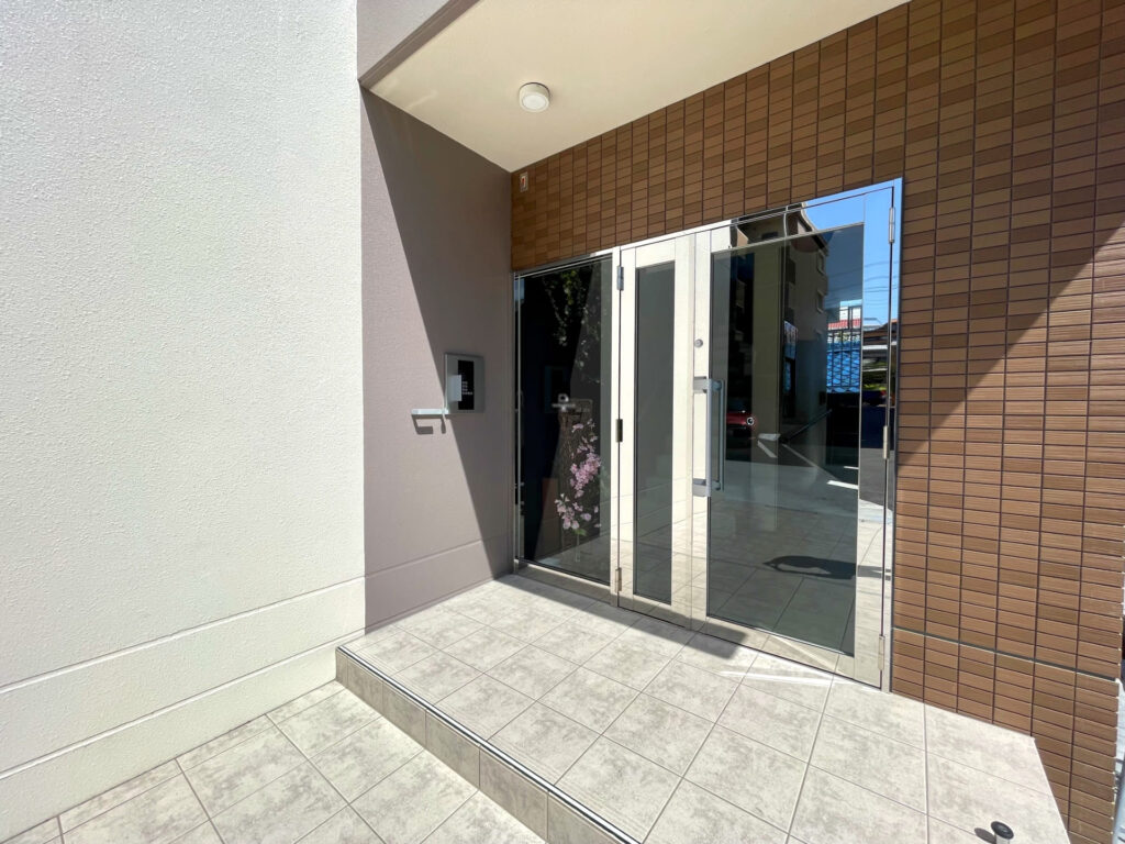 清潔感のある賃貸マンションのオートロック付きエントランス。タイルが綺麗に掃除されており、管理が行き届いている様子。