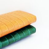 オレンジとグリーンの鮮やかなクロコダイル革財布が重なっている様子。竹斑の美しい模様が特徴的