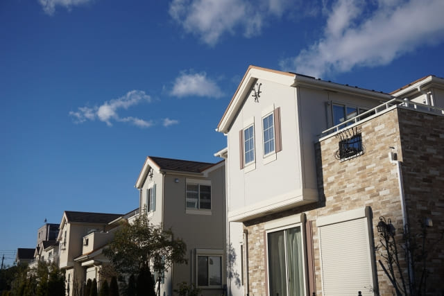 青空の下に並ぶ、モダンで明るい外壁とレンガ調のデザインが特徴的な新築一戸建て住宅の町並み。