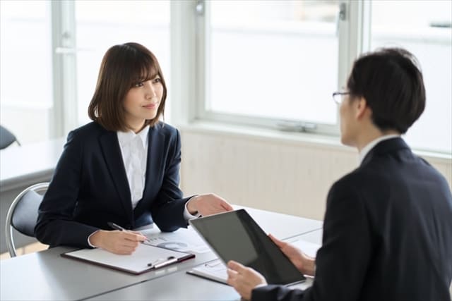 不動産仲介業者の店舗でスタッフから説明を受ける顧客の相談風景