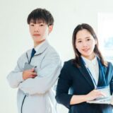 Image of cooperation between a construction company site manager in workwear with a tablet and a prime contractor representative in a suit with a laptop.