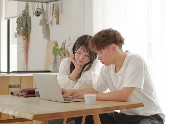 A 30s couple looking at a laptop together at home, searching for ideal homes and discussing their financial planning online.
