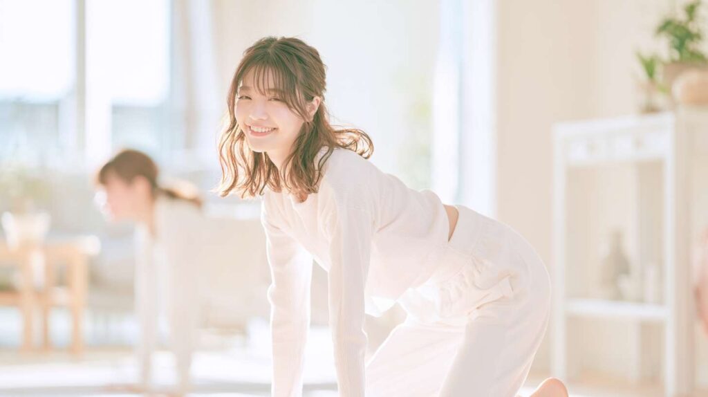 自宅のリビングでキャット&ドッグのポーズをしてストレッチする女性