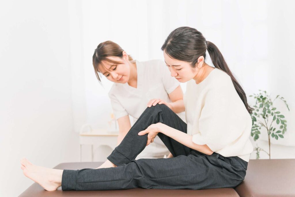 施術者が患者の膝を支えながら、脚のストレッチを行っている様子