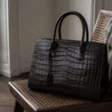 A crocodile leather handbag resting on a chair in a calm, elegant interior setting